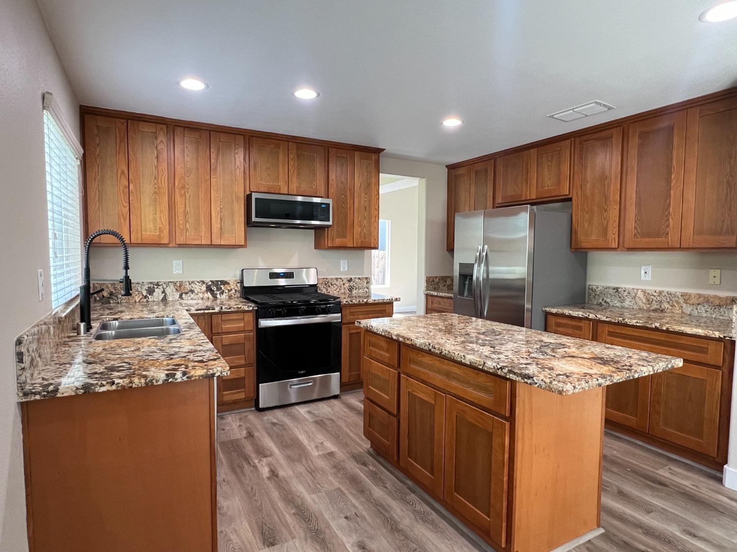 a kitchen with stainless steel appliances granite countertop wooden cabinets stove and refrigerator