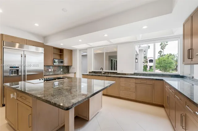 a large kitchen with granite countertop a large counter top and stainless steel appliances