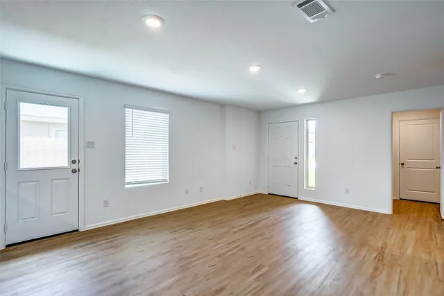 an empty room with wooden floor and windows
