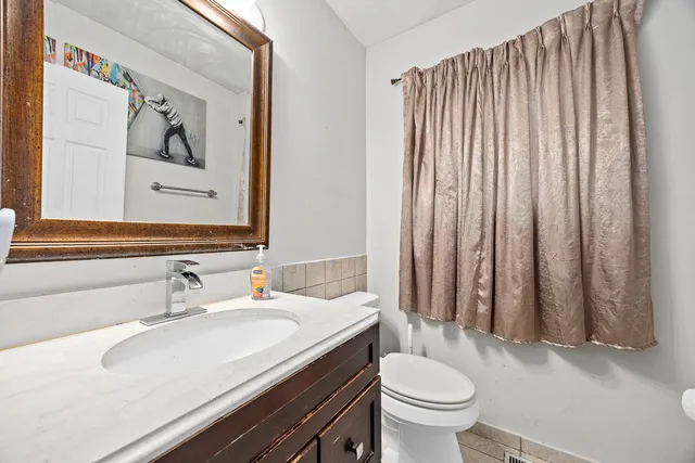 a bathroom with a granite countertop sink and a toilet