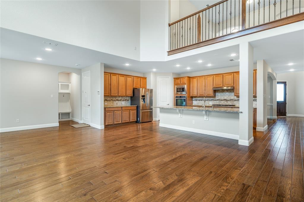 4560 Cheetah Trail Frisco, TX 75034 - Photo 6 of 38 an empty room with wooden floor and way to kitchen
