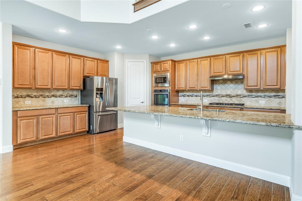 4560 Cheetah Trail Frisco, TX 75034 - Photo 9 of 38 a kitchen with stainless steel appliances a refrigerator and wooden floor