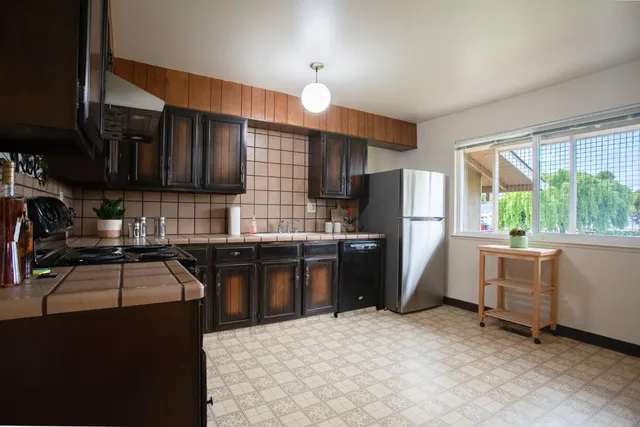a kitchen with granite countertop a refrigerator and a stove top oven
