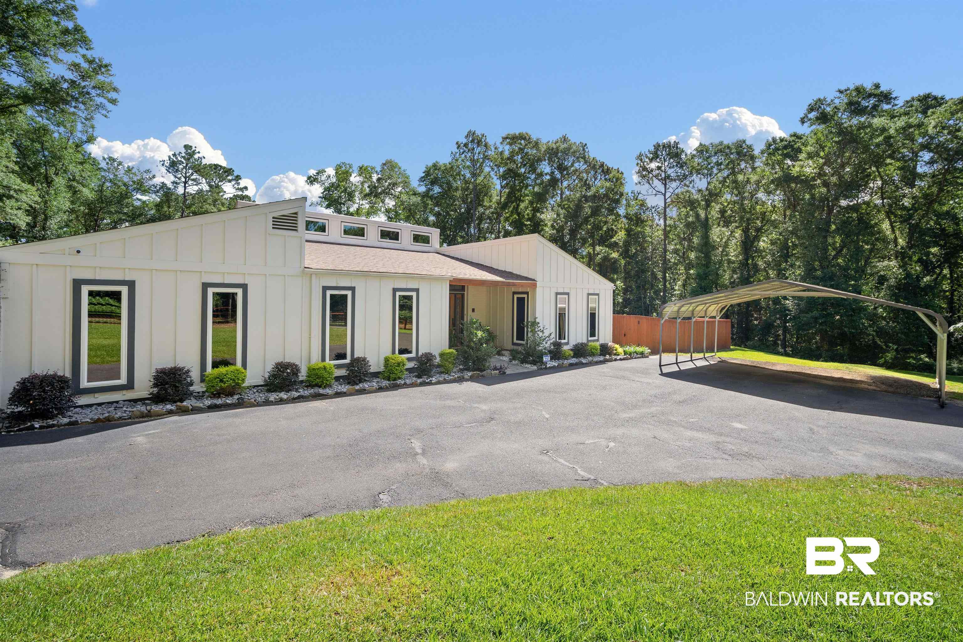 7912 Yorkhaven Road Mobile, AL 36695 - Photo 1 of 41 Mid-century modern home with board and batten siding, asphalt driveway, a detached carport, and a front lawn