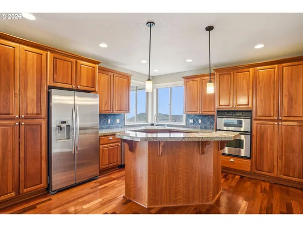 a kitchen with stainless steel appliances granite countertop a refrigerator a sink and a wooden cabinets