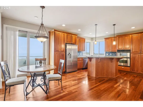 a kitchen with stainless steel appliances kitchen island granite countertop a refrigerator a stove and a wooden floors
