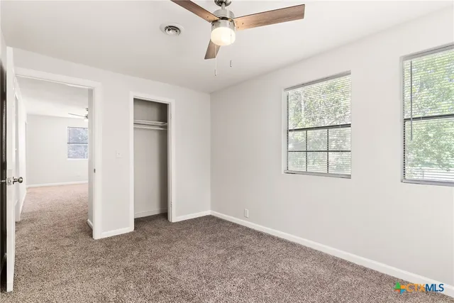 an empty room with windows and ceiling fan