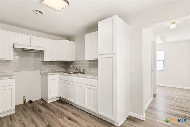 a kitchen with stainless steel appliances granite countertop a refrigerator sink and white cabinets