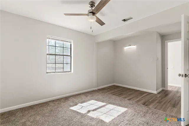 an empty room with a window and ceiling fan