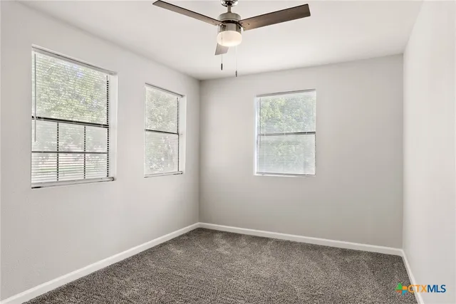 an empty room with windows and fan