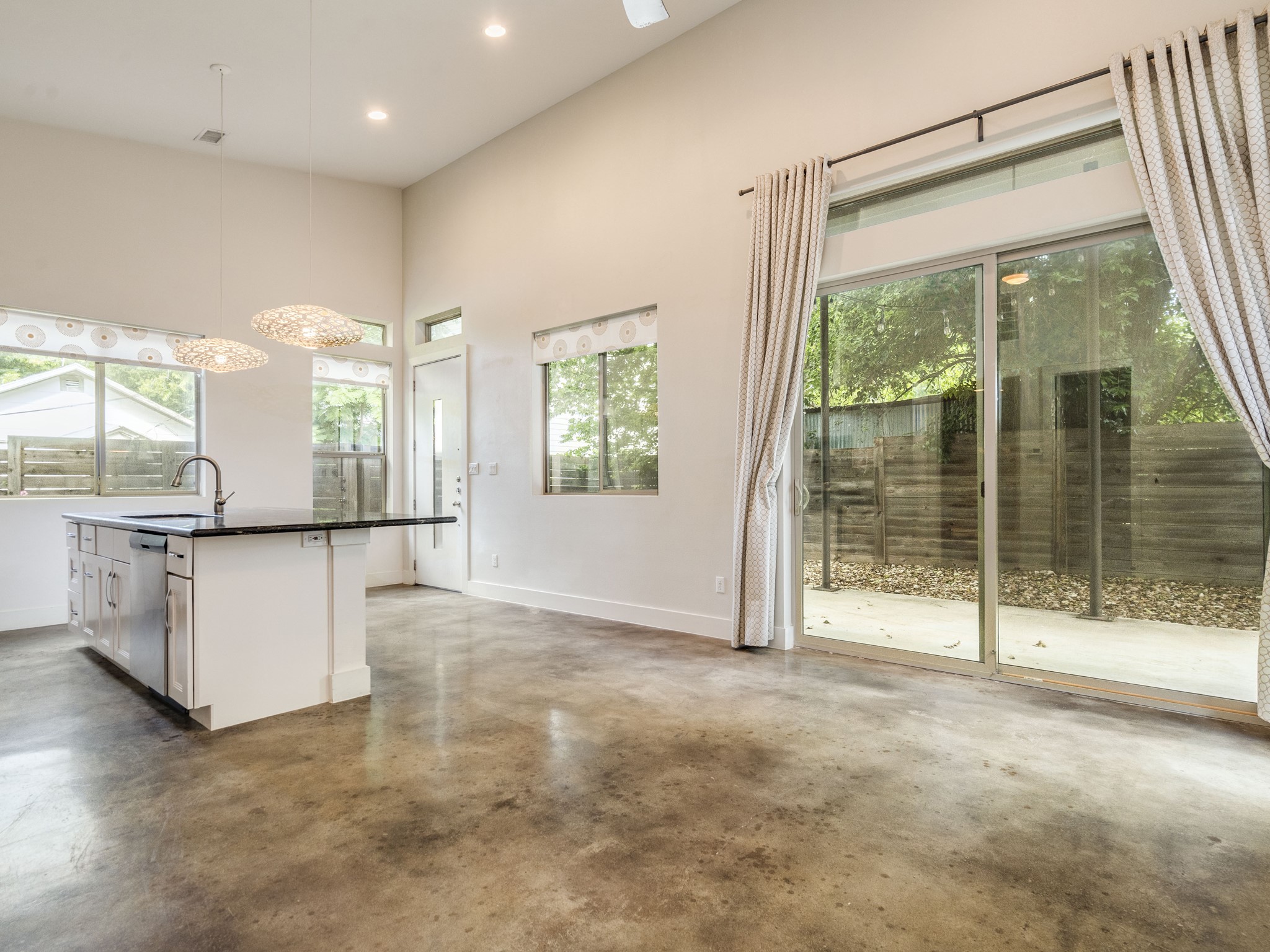 1404 Singleton Avenue, Unit B Austin, TX 78702 - Photo 8 of 21 An open-concept living space with concrete flooring flows into a modern kitchen island, creating a harmonious and functional layout.