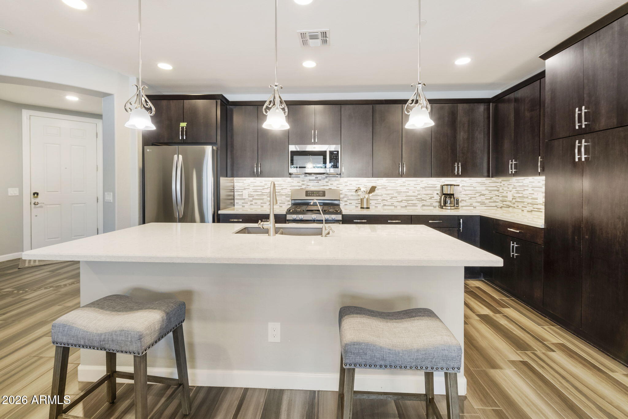 4777 South Fulton Ranch Boulevard, Unit 1086 Chandler, AZ 85248 - Photo 11 of 67 a kitchen with kitchen island a sink cabinets and wooden floor