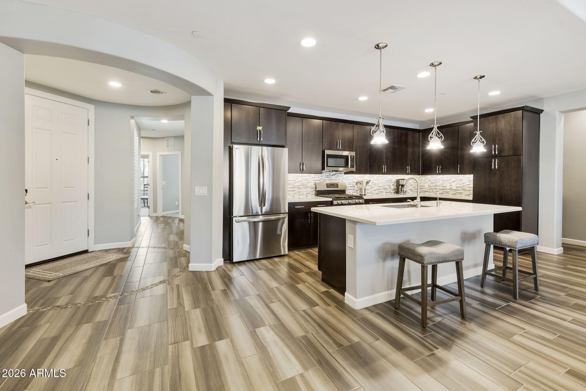 4777 South Fulton Ranch Boulevard, Unit 1086 Chandler, AZ 85248 - Photo 10 of 67 a kitchen with stainless steel appliances kitchen island granite countertop a refrigerator a stove and a sink with wooden floor
