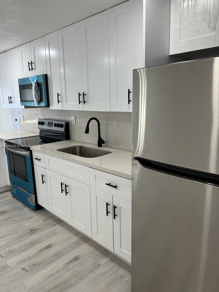 5836 Hope Street Hollywood, FL 33021 - Photo 11 of 24 a kitchen with a refrigerator sink and white cabinets