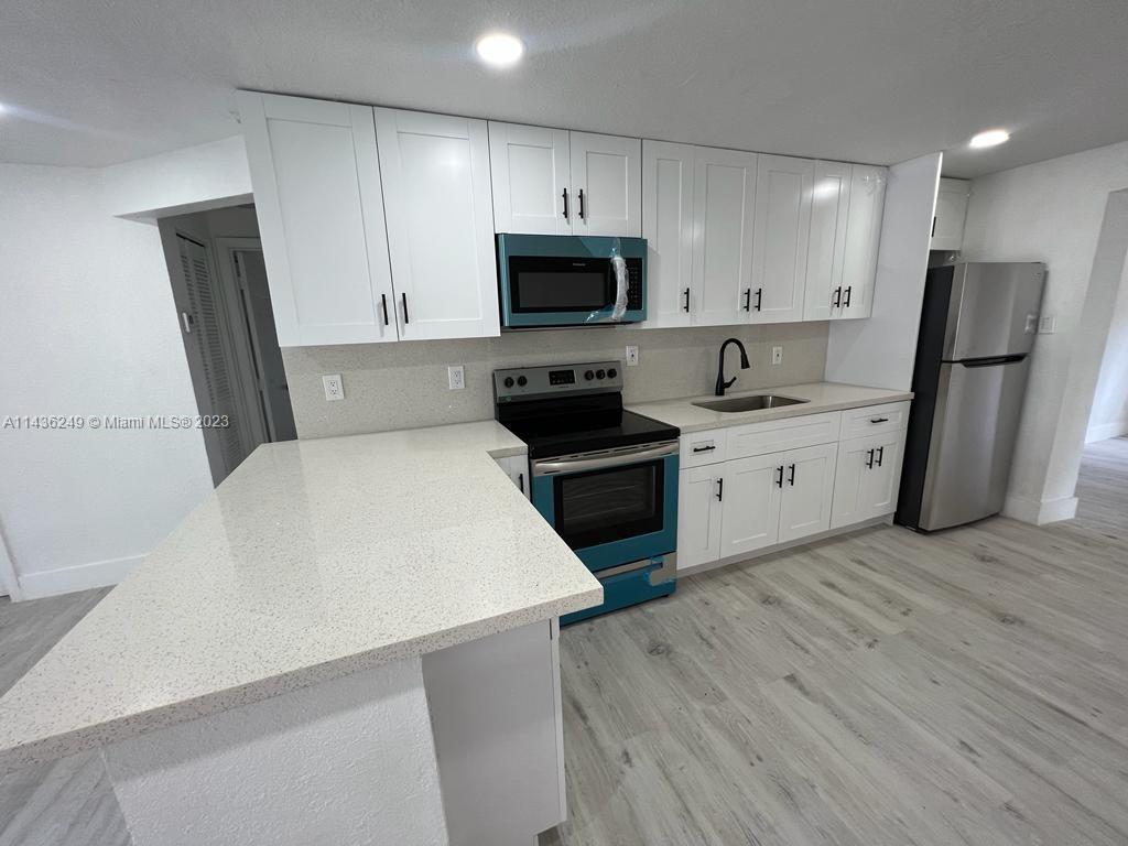 5836 Hope Street Hollywood, FL 33021 - Photo 6 of 24 a kitchen with a sink a microwave a refrigerator and cabinets
