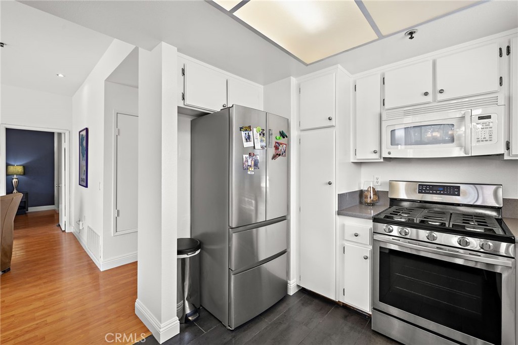 17641 Sergio Circle, Unit 203 Huntington Beach, CA 92647 - Photo 11 of 25 a kitchen with stainless steel appliances granite countertop a refrigerator stove and white cabinets