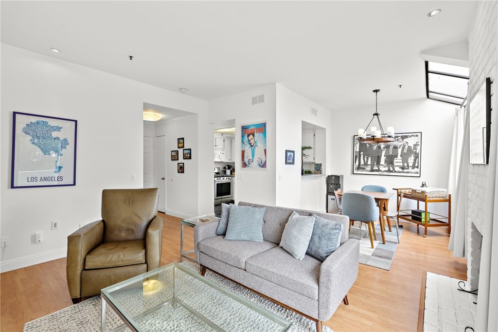 17641 Sergio Circle, Unit 203 Huntington Beach, CA 92647 - Photo 7 of 25 a living room with furniture and a dining table with wooden floor