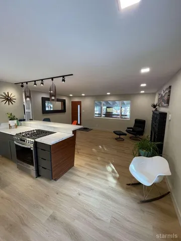 a large kitchen with stainless steel appliances kitchen island granite countertop a sink dishwasher and a stove with wooden floor