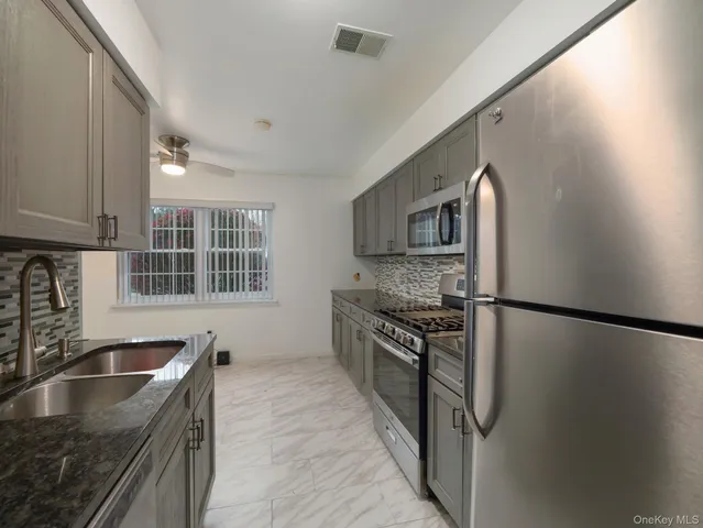 a kitchen with granite countertop a sink stove and refrigerator