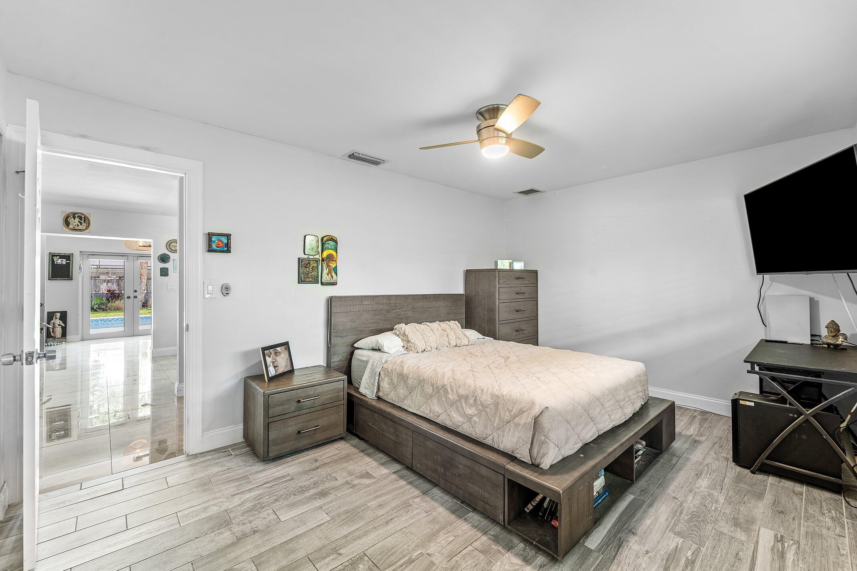 581 Northwest 13th Drive Boca Raton, FL 33486 - Photo 20 of 39 a bedroom with a bed a flat screen tv and a chandelier