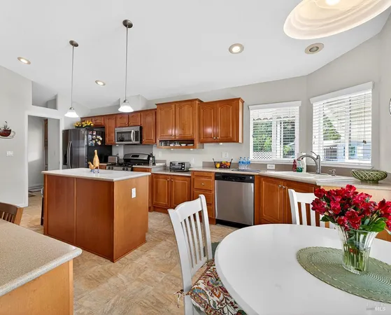a kitchen with stainless steel appliances granite countertop a refrigerator a sink dishwasher with a dining table and chairs