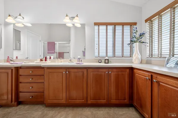 a bathroom with a double vanity sink a large mirror and a window