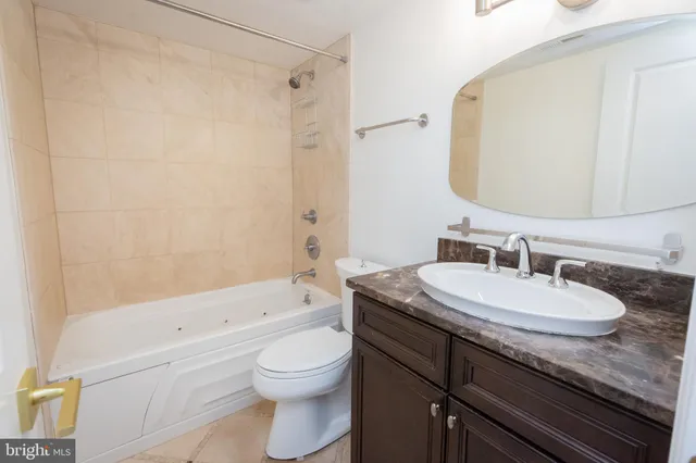 a bathroom with a granite countertop sink a toilet and a mirror