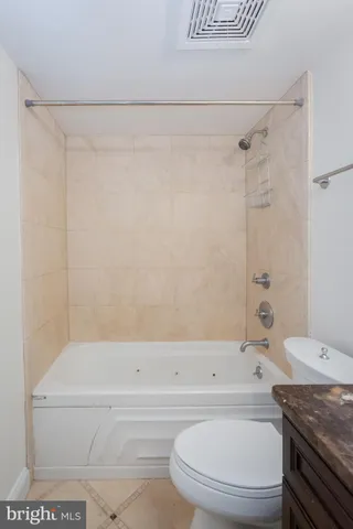 a bathroom with a granite countertop bathtub shower sink vanity and toilet