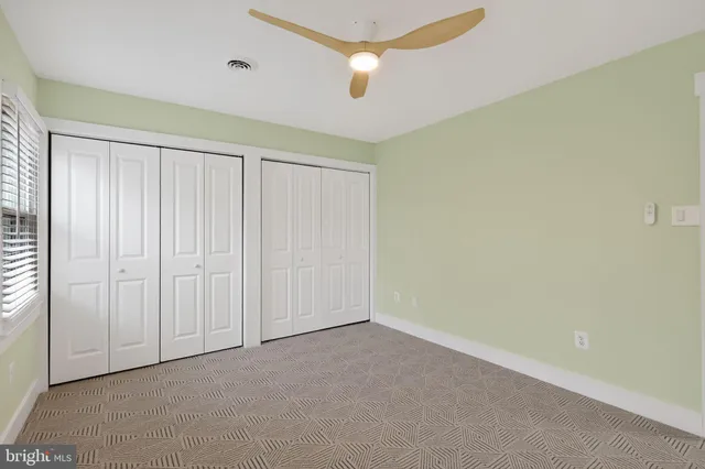 an empty room with a ceiling fan and a window