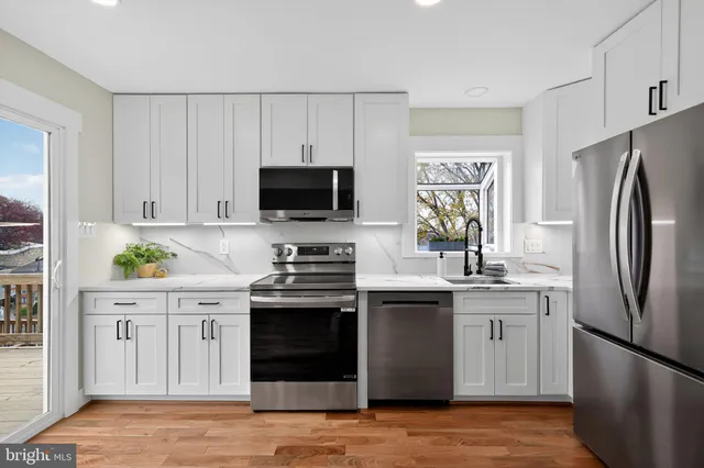 a kitchen with stainless steel appliances a stove a sink a refrigerator a microwave a cabinets and wooden floor