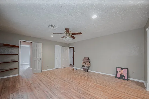 a view of empty room with wooden floor and fan