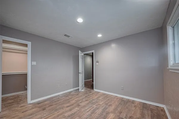 a view of an empty room with wooden floor and closet
