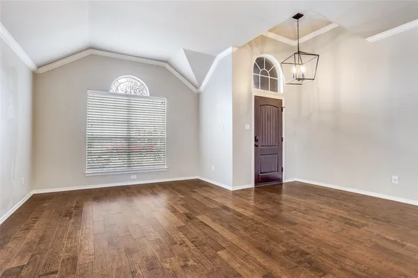 an empty room with wooden floor cabinet and windows