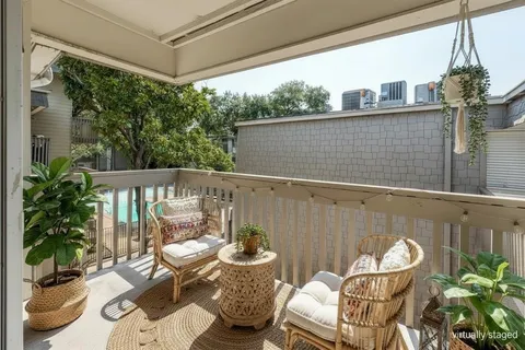 a view of a balcony with chairs and a potted plant