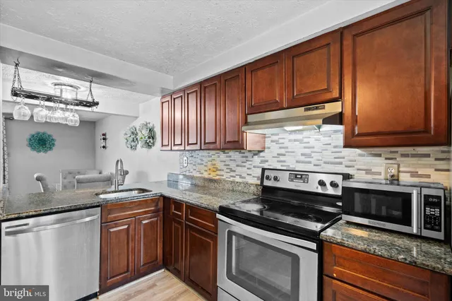 a kitchen with stainless steel appliances granite countertop wooden cabinets stove top oven and sink