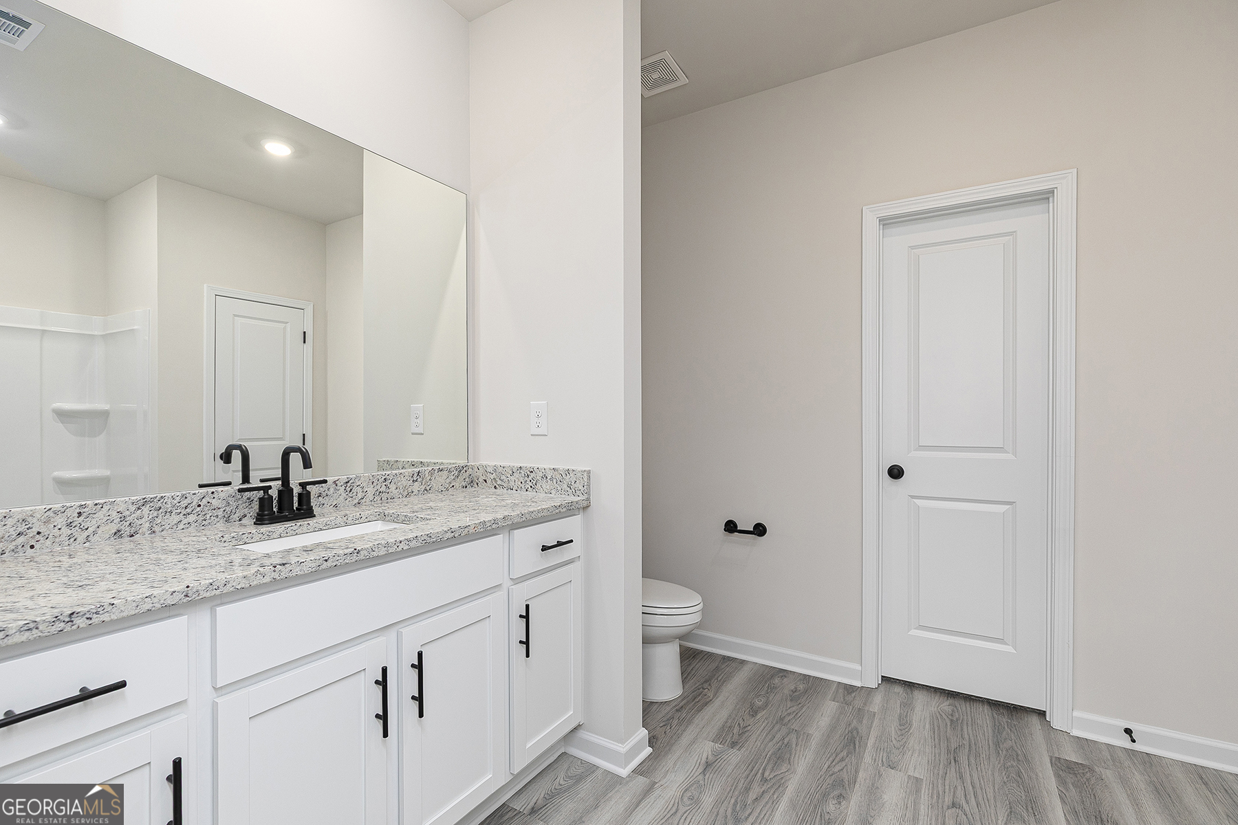 217 Darter Court Hoschton, GA 30548 - Photo 14 of 23 a bathroom with a granite countertop sink a toilet and a large mirror