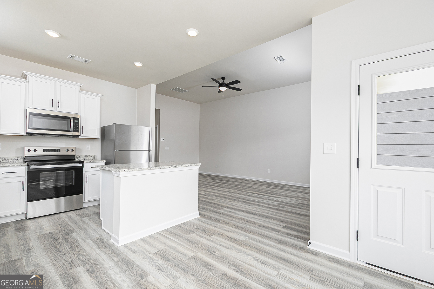 217 Darter Court Hoschton, GA 30548 - Photo 10 of 23 a kitchen with stainless steel appliances a stove top oven a sink and a refrigerator with wooden floor