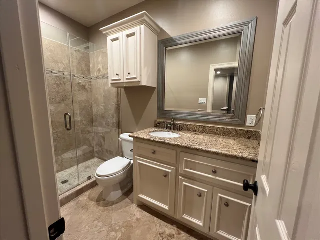 a bathroom with a granite countertop sink toilet and shower