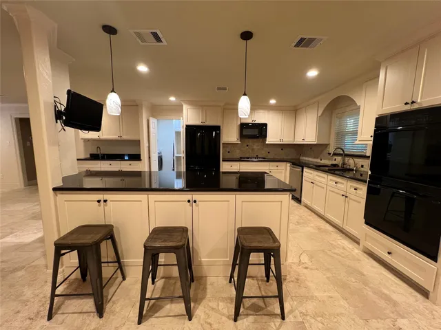 a kitchen with stainless steel appliances kitchen island granite countertop a sink and a stove top oven with wooden floor
