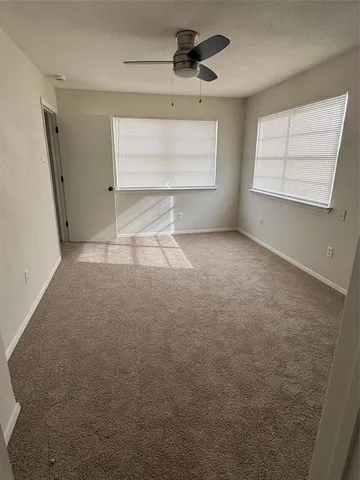 an empty room with windows and fan