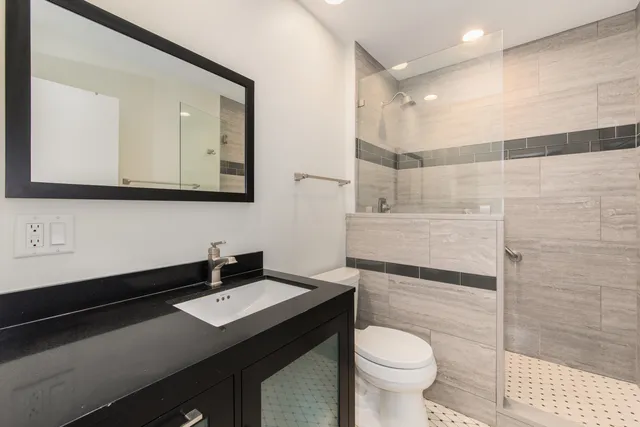 a bathroom with a sink a toilet a mirror and shower