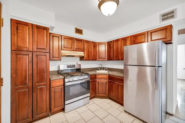 a kitchen with stainless steel appliances granite countertop a refrigerator stove top oven and cabinets