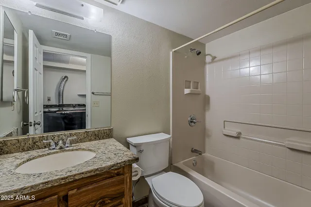 a bathroom with a granite countertop toilet sink and mirror