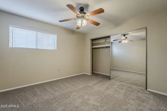 an empty room with closet and a ceiling fan