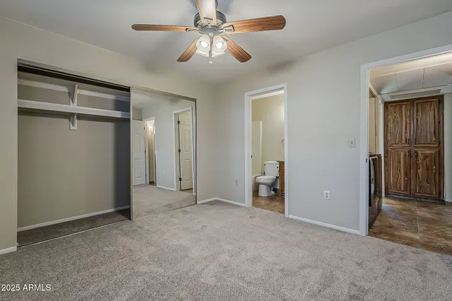 an empty room with closet and a chandelier fan