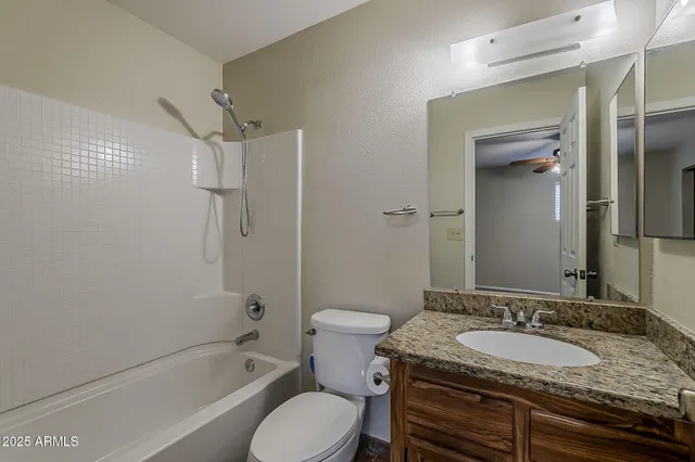 a bathroom with a granite countertop toilet sink and mirror