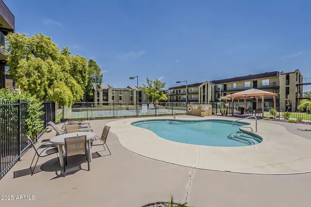 a view of a swimming pool with lawn chairs and a barbeque