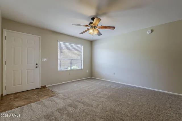 a view of an empty room with window and chandelier fan
