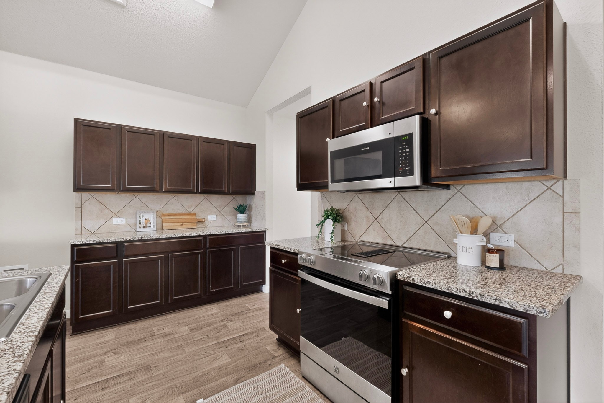 5905 Diamondleaf Bend Austin, TX 78724 - Photo 12 of 38 Kitchen featuring dark wood cabinetry, granite countertops, stainless steel appliances, a tile backsplash, and wood-finish flooring