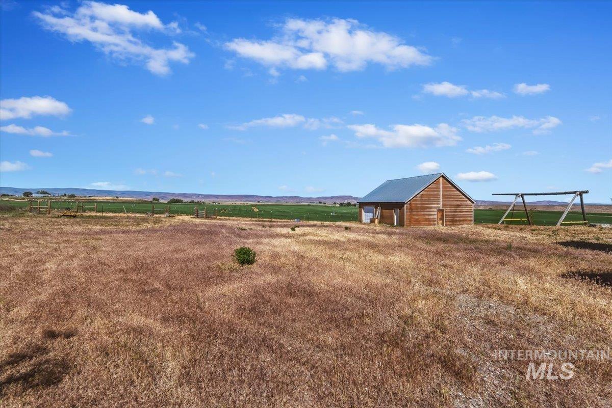 2331 Gulley Road Homedale, ID 83628 - Photo 43 of 46 Rural landscape featuring a wood-sided outbuilding with a metal roof, surrounded by extensive fields